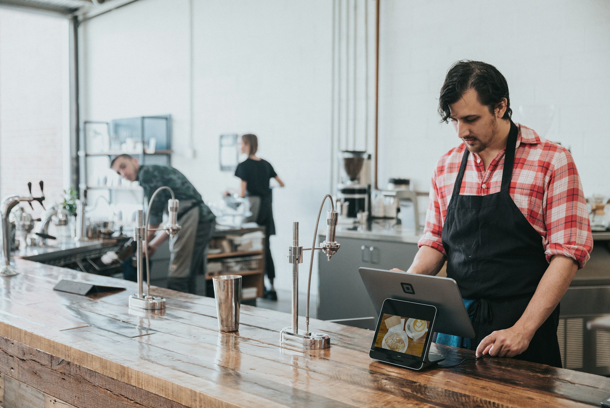 A shop owner working behind the counter, checking a tablet